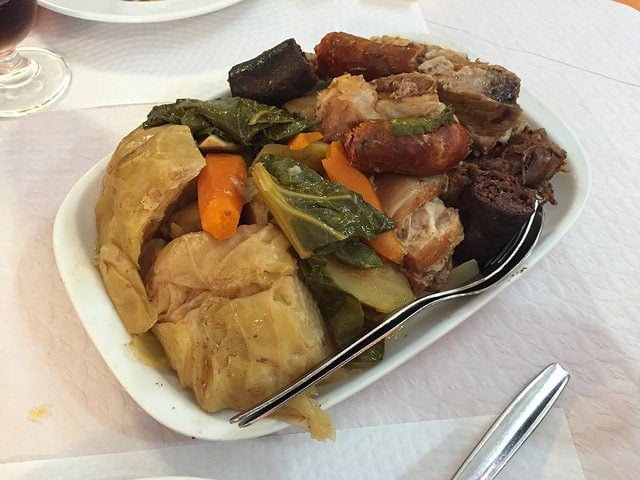 A heaping plate of Portuguese cozido: stew with several different types of meat and vegetables.
