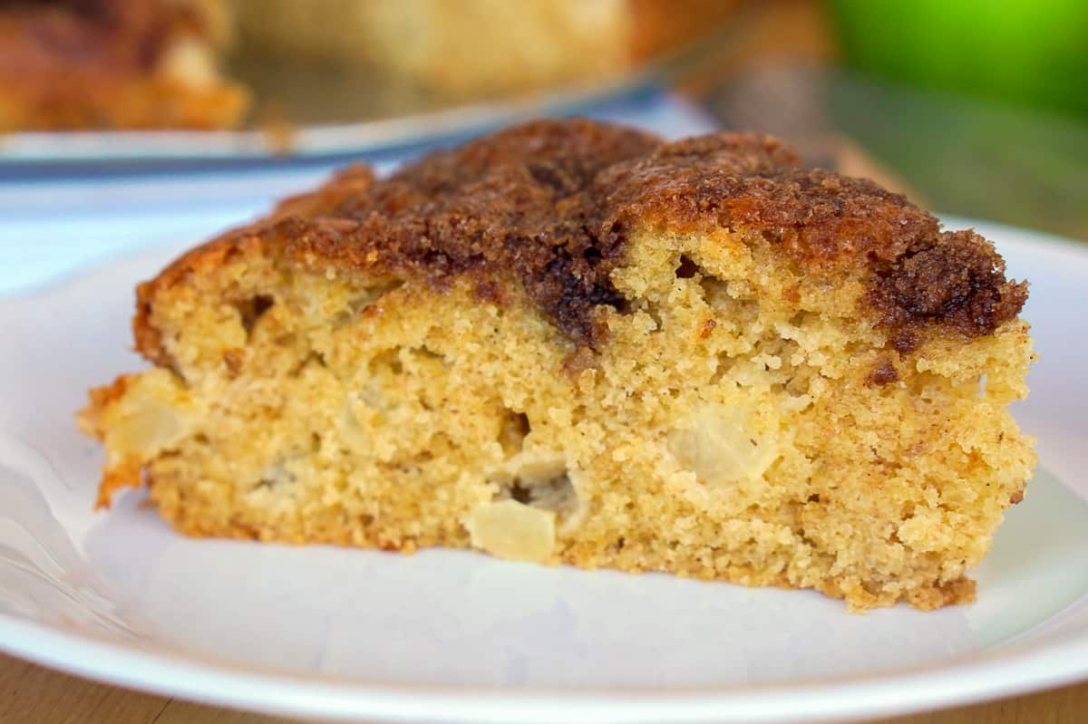 Close-up of a slice of apple olive oil cake on a white plate.