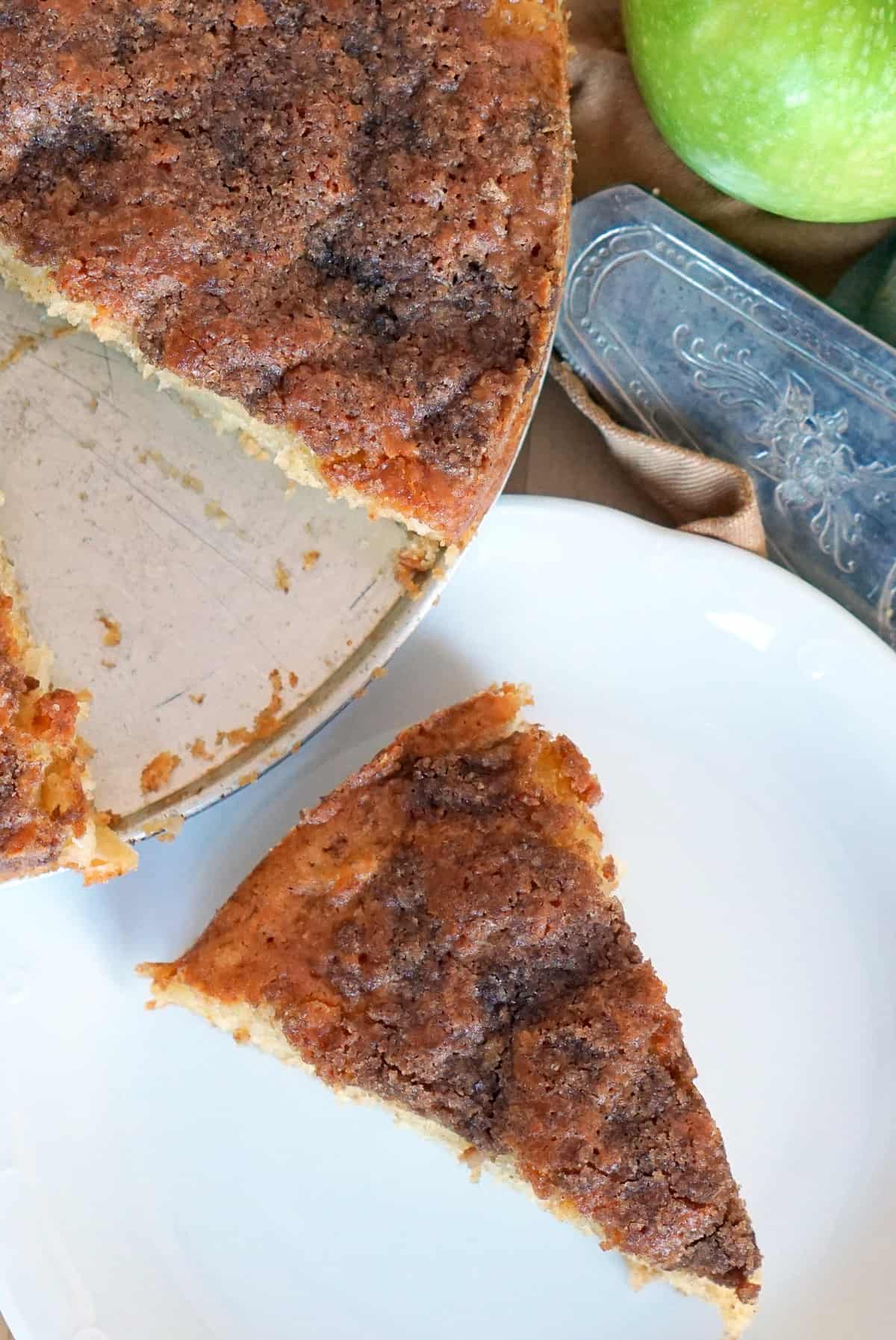 Slice of apple olive oil cake on a white plate