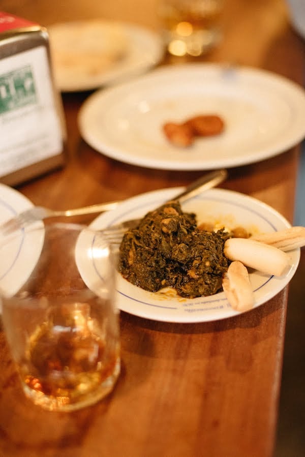 A small white plate of stewed spinach and chickpeas with two small breadsticks and a fork.