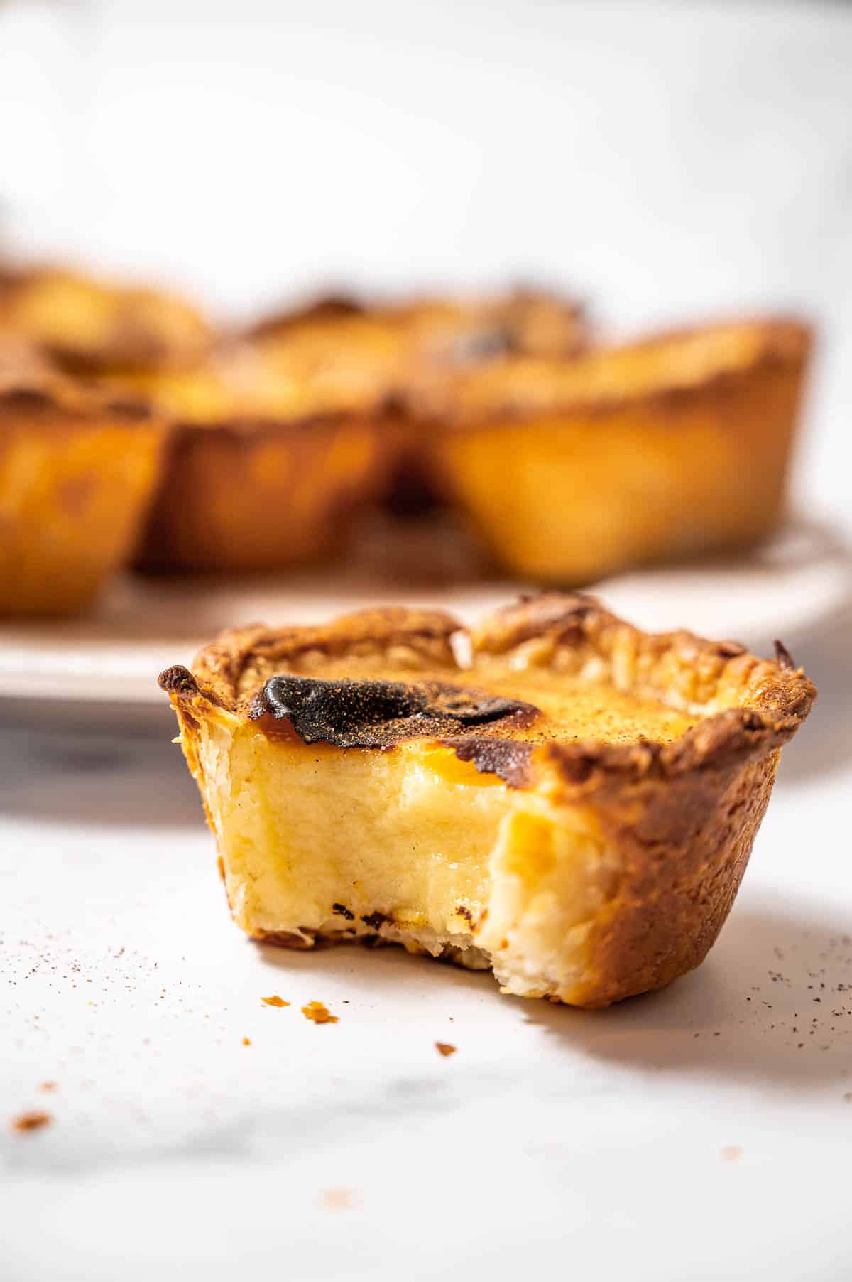 Close up of a Portuguese custard tart with a bite taken out of it.