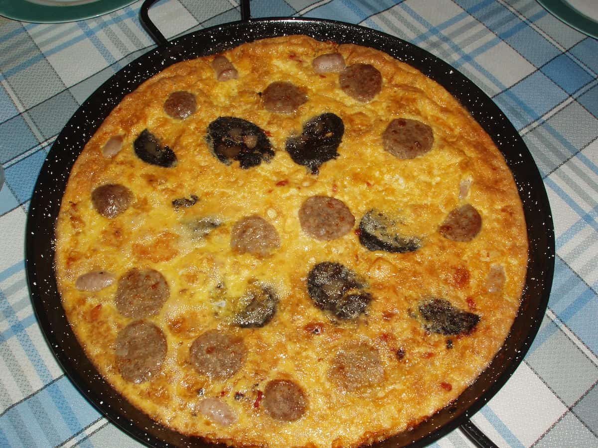 Overhead shot of a rice dish in a round pan with sausages and a glossy crust.