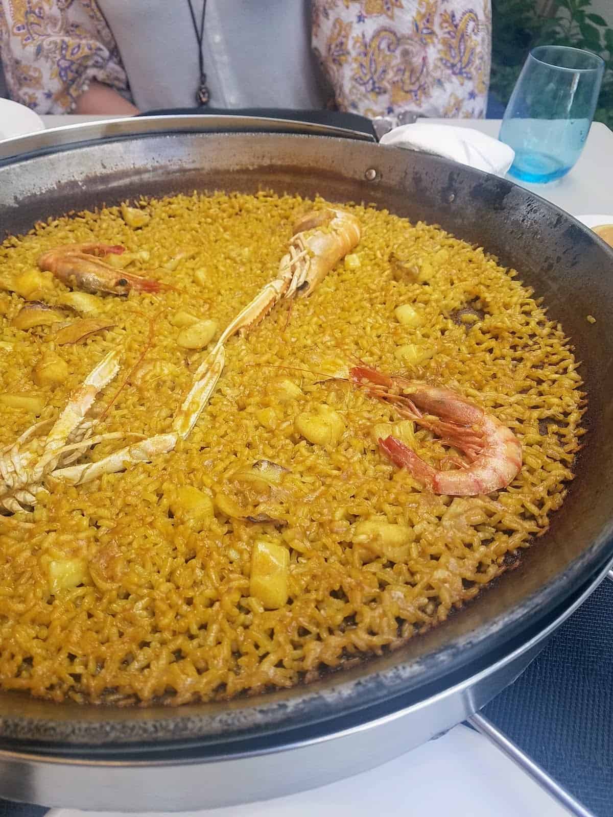 Large metal pan of seafood paella topped with shellfish.