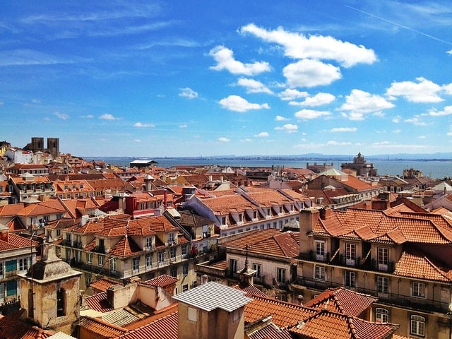 Panoramic view of Chiado's tiled rooftops with the Tagus River in the background.