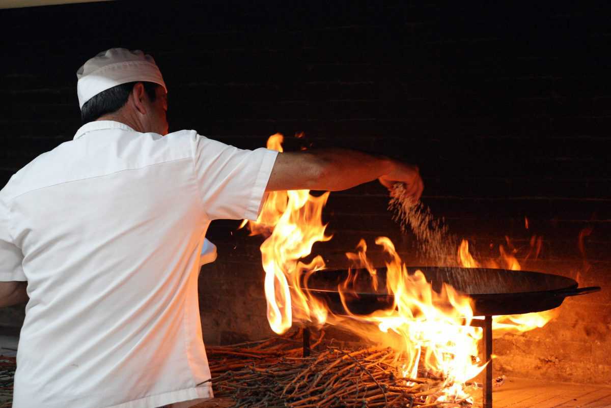 Chef cooking paella on an open flame