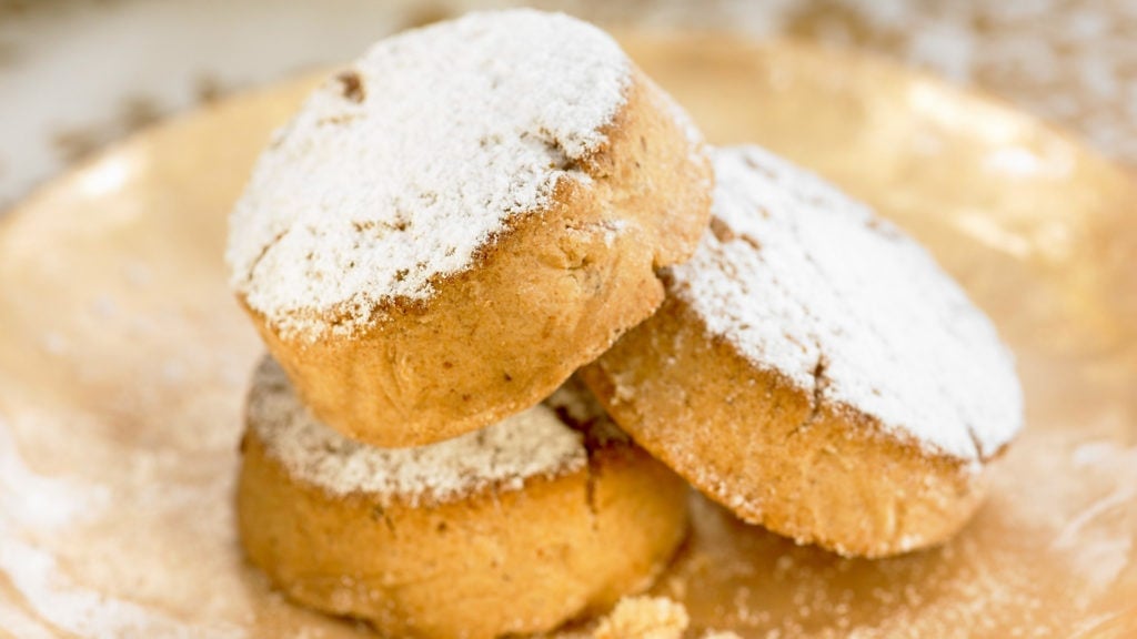 Three round polvorones, or Spanish Christmas cookies, dusted with powdered sugar.