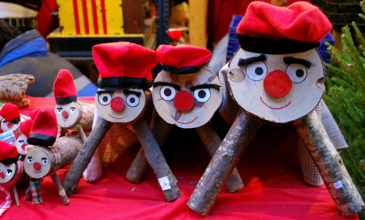 Large, medium, and small logs decorated with smiling faces and wearing red hats