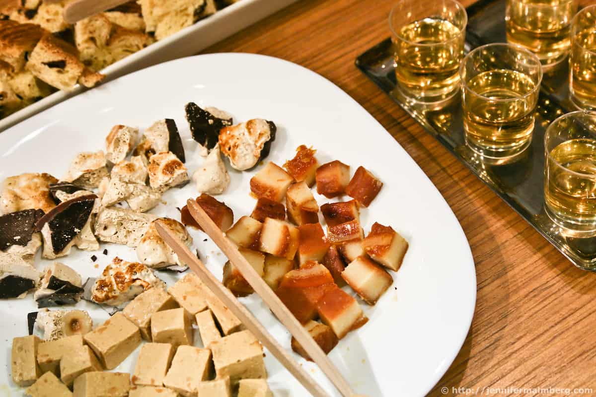 Spanish almond nougat candy on a white plate next to small glasses of liquor
