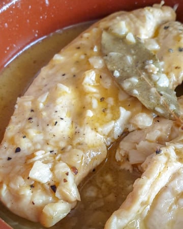 Chicken in white wine and garlic sauce. Spanish pollo en salsa in a clay dish.