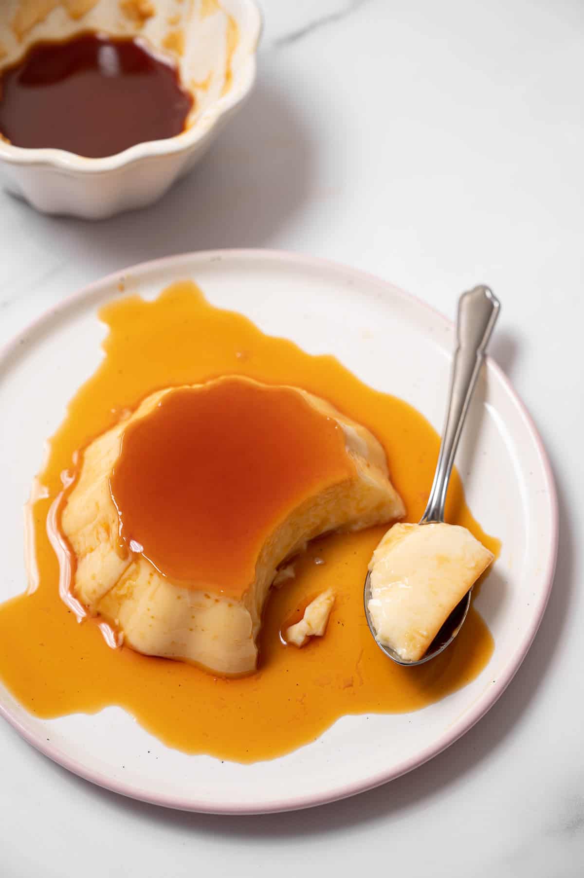 Spanish flan on a white plate with a spoonful removed.