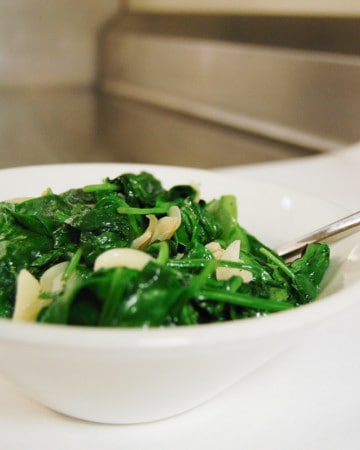 Sauteed spinach and garlic in a white bowl.