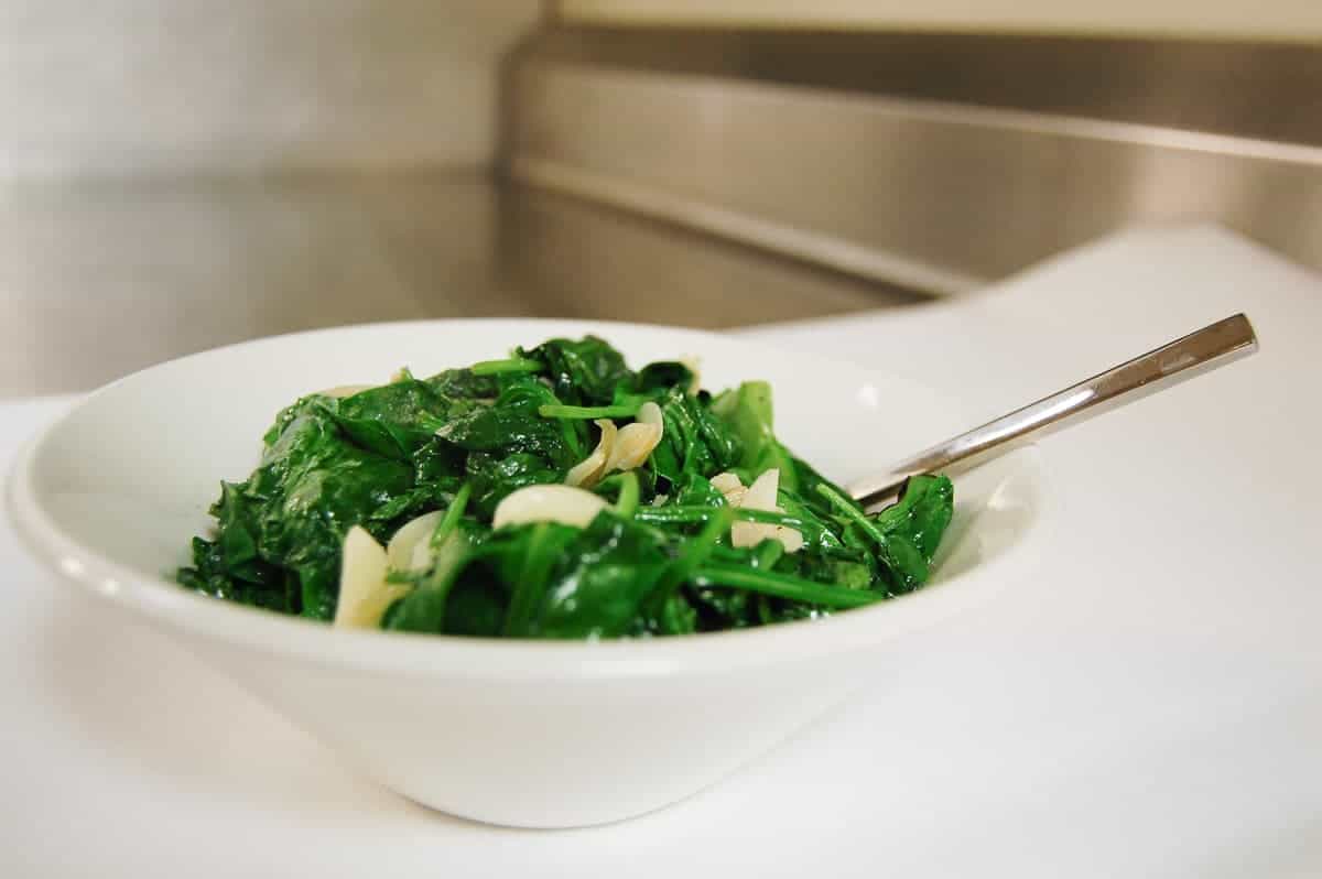 Sauteed spinach and garlic in a white bowl.