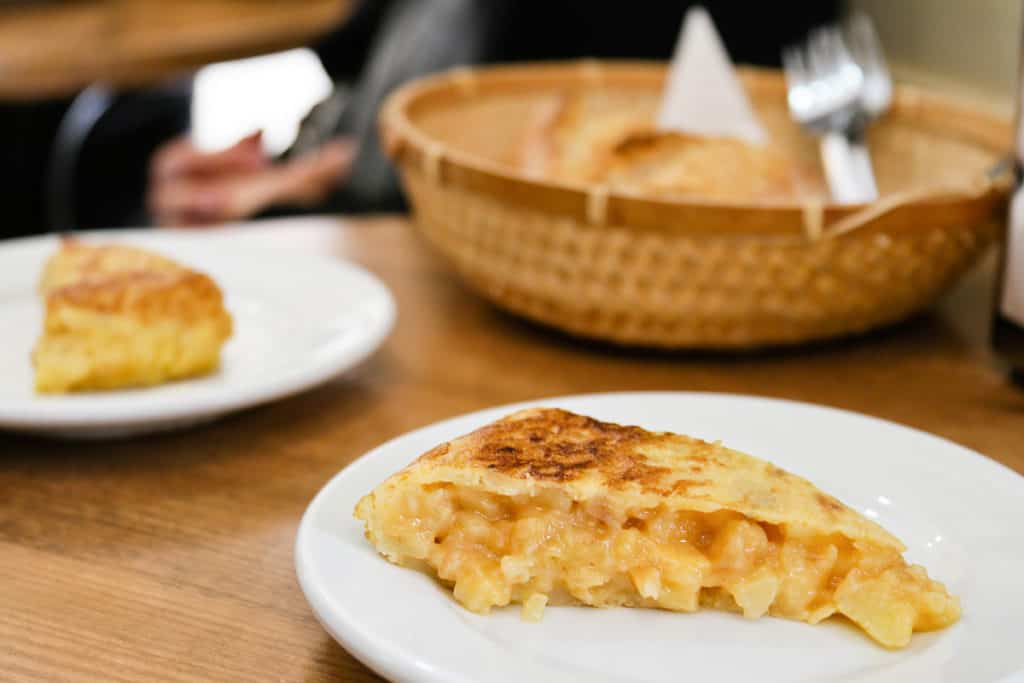 Slices of potato omelet on white plates