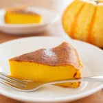 Slice of crustless pumpkin cheesecake on a white plate with a metal fork