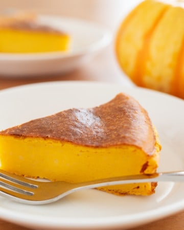 Slice of crustless pumpkin cheesecake on a white plate with a metal fork