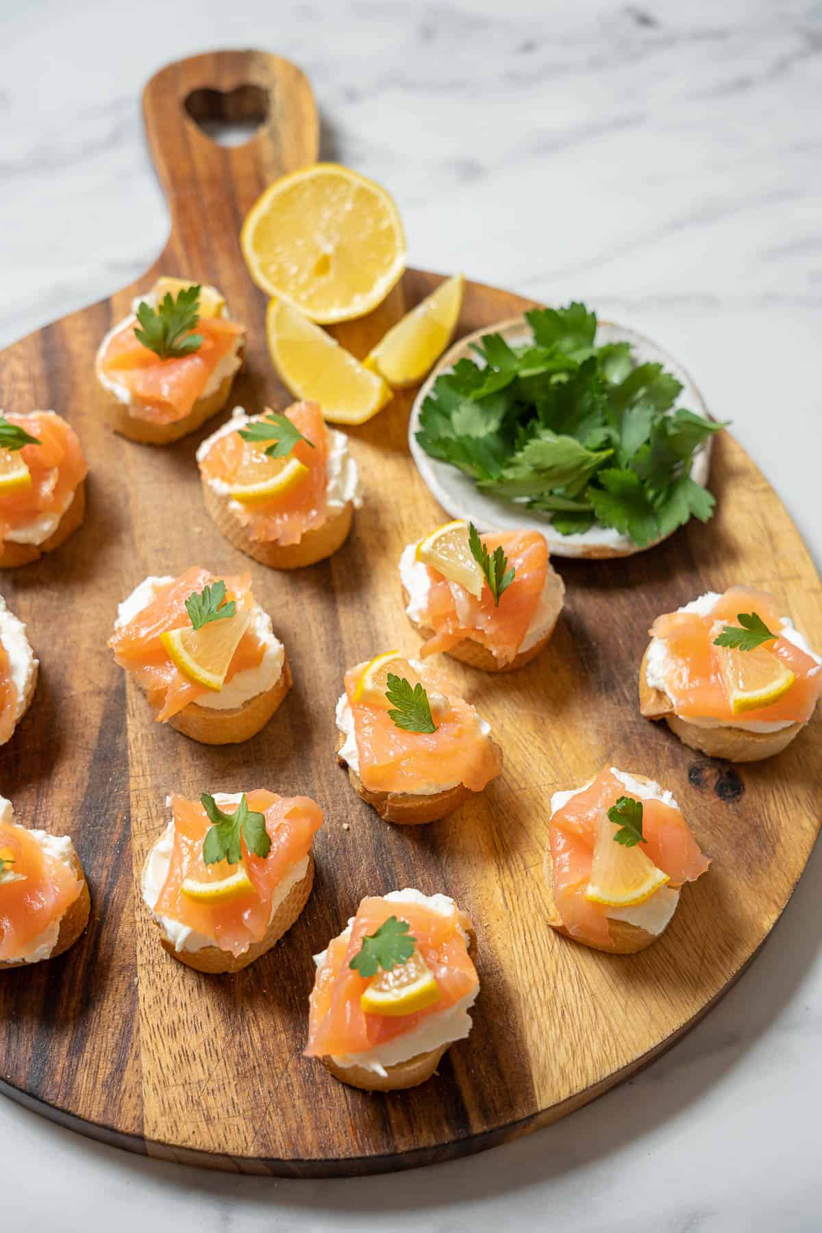 Smoked salmon and cream cheese mini toasts on a wooden cutting board