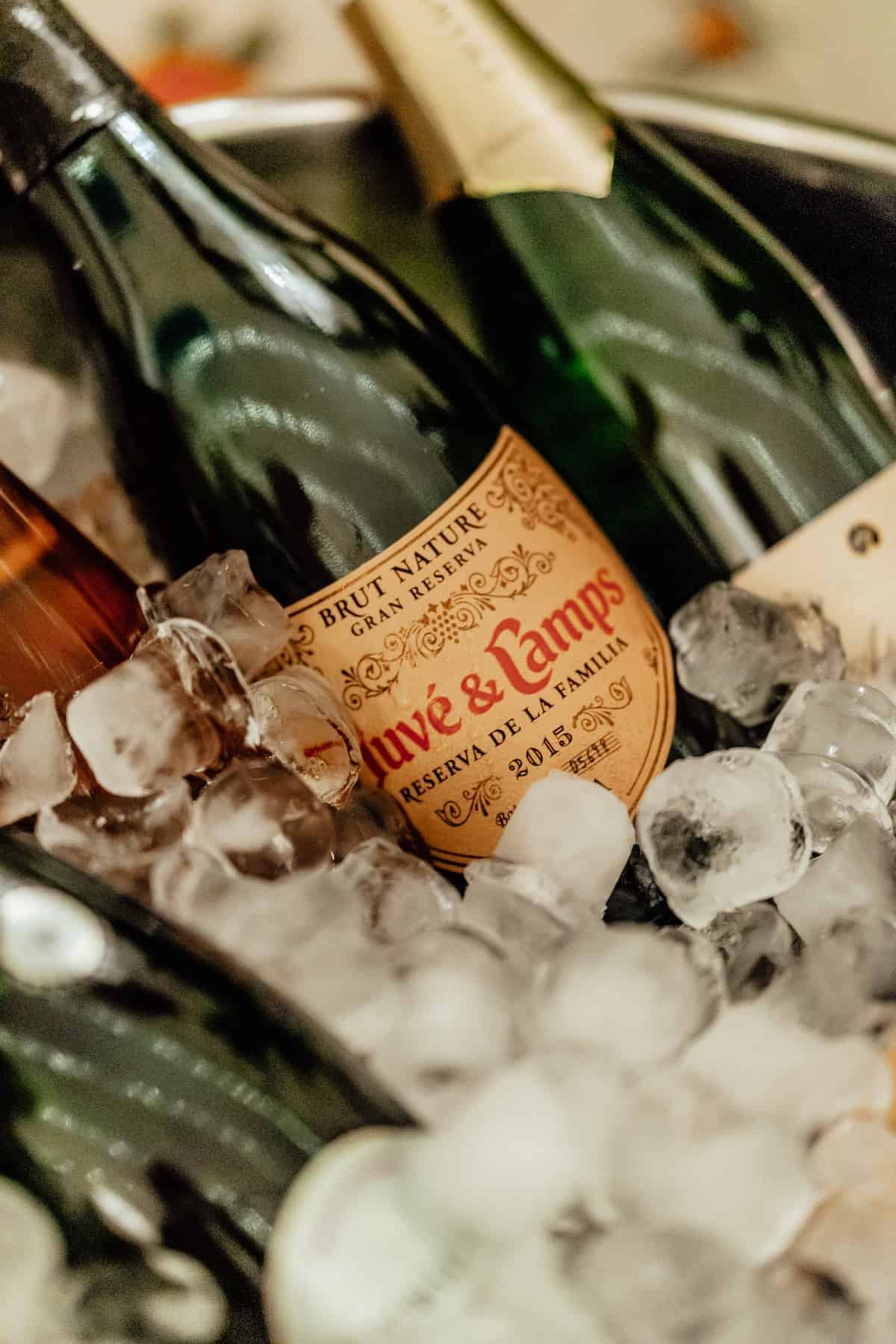 Close up of cava bottles chilling in a bucket of ice.