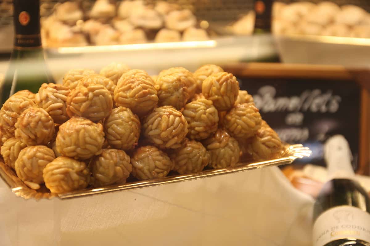 Tray of round ball-shaped sweets covered with pine nuts.