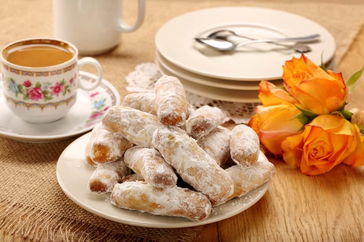 A plate of alfajores with tea and flowers on the table