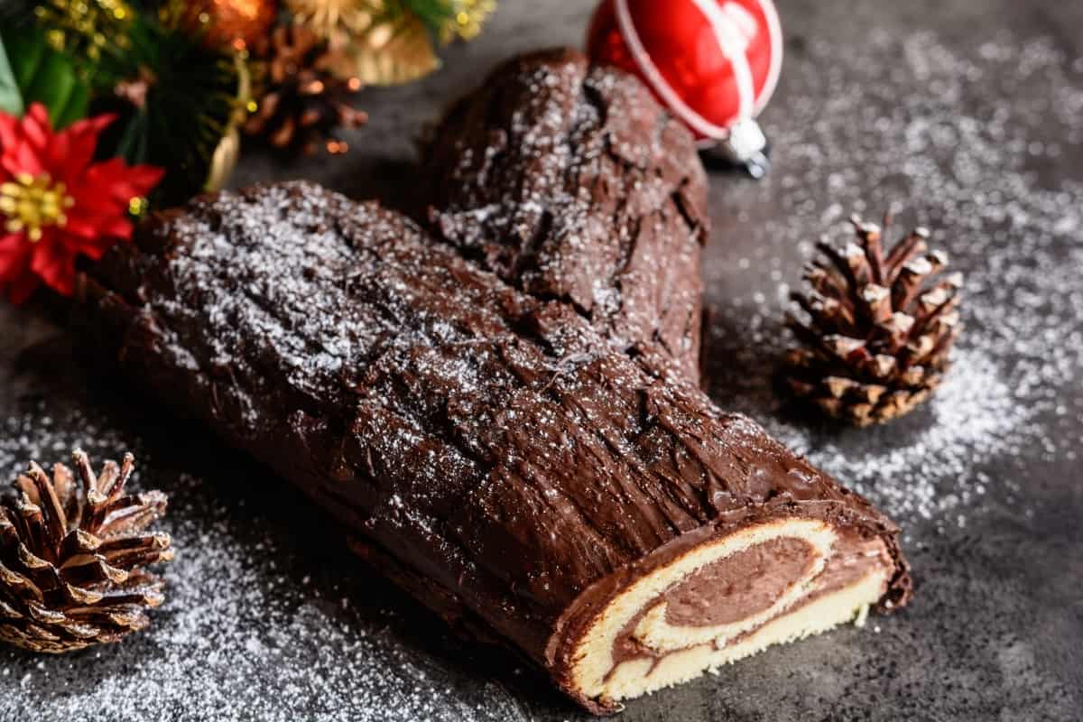 Spanish tronco de Navidad Christmas dessert with pine cones and Christmas bulbs in the background.