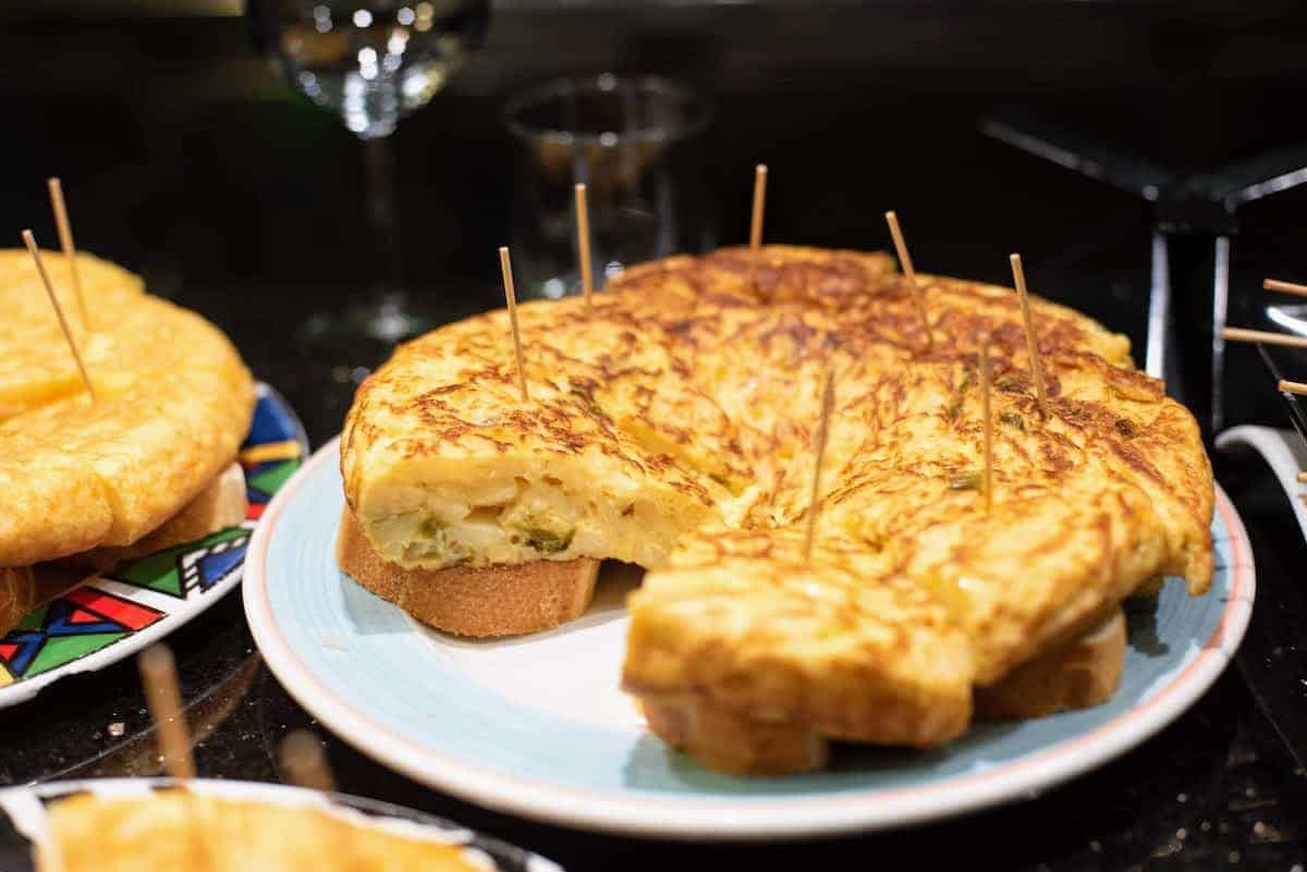 Slices of potato and pepper omelet served skewered atop pieces of bread
