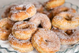 Sugar covered fried donuts in a glass dish.