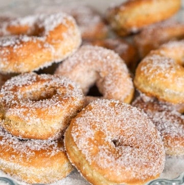 Sugar covered fried donuts in a glass dish.