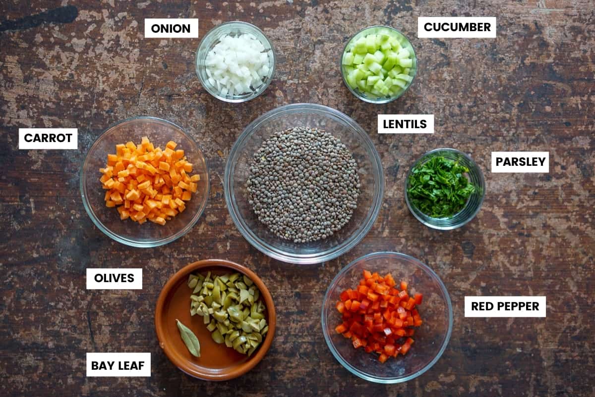 Lentil salad ingredients with labels: carrots, onion, cucumber, parsley, red pepper, olives, bay leaf, lentils.