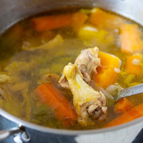 Pot of chicken stock with chicken and vegetables inside