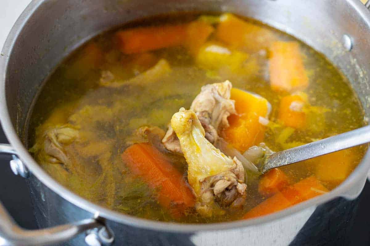 Pot of chicken stock with chicken and vegetables inside