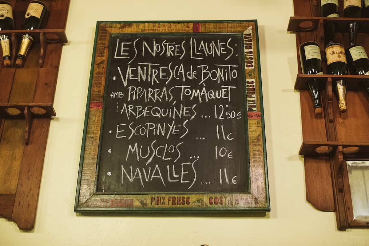 Chalkboard menu on a wall listing a restaurant's specialties in Catalan.