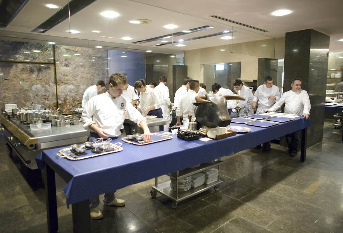 Interior shot of a busy kitchen with people in white cook's jackets cooking.