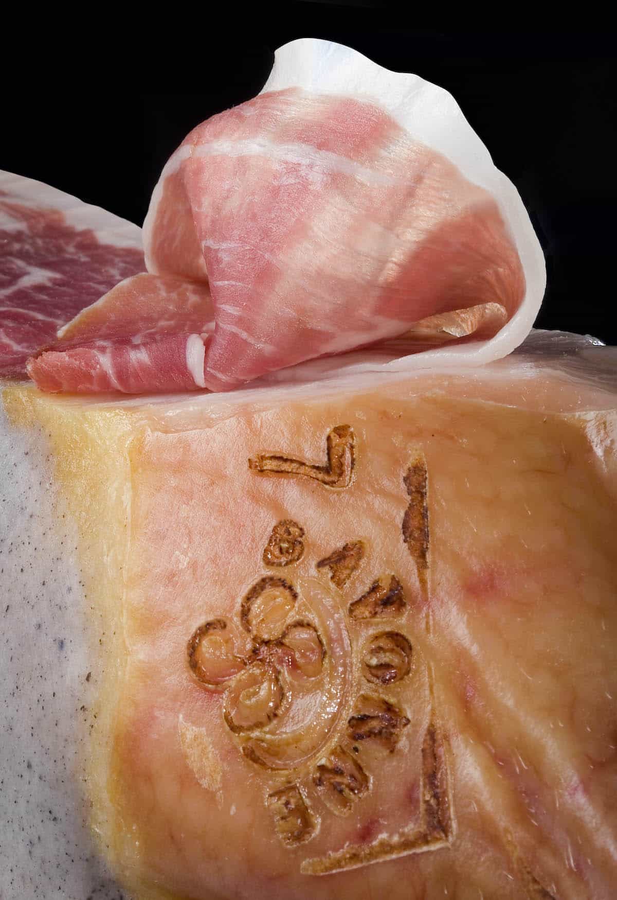 A slice of cured ham lying atop the leg it was carved from.