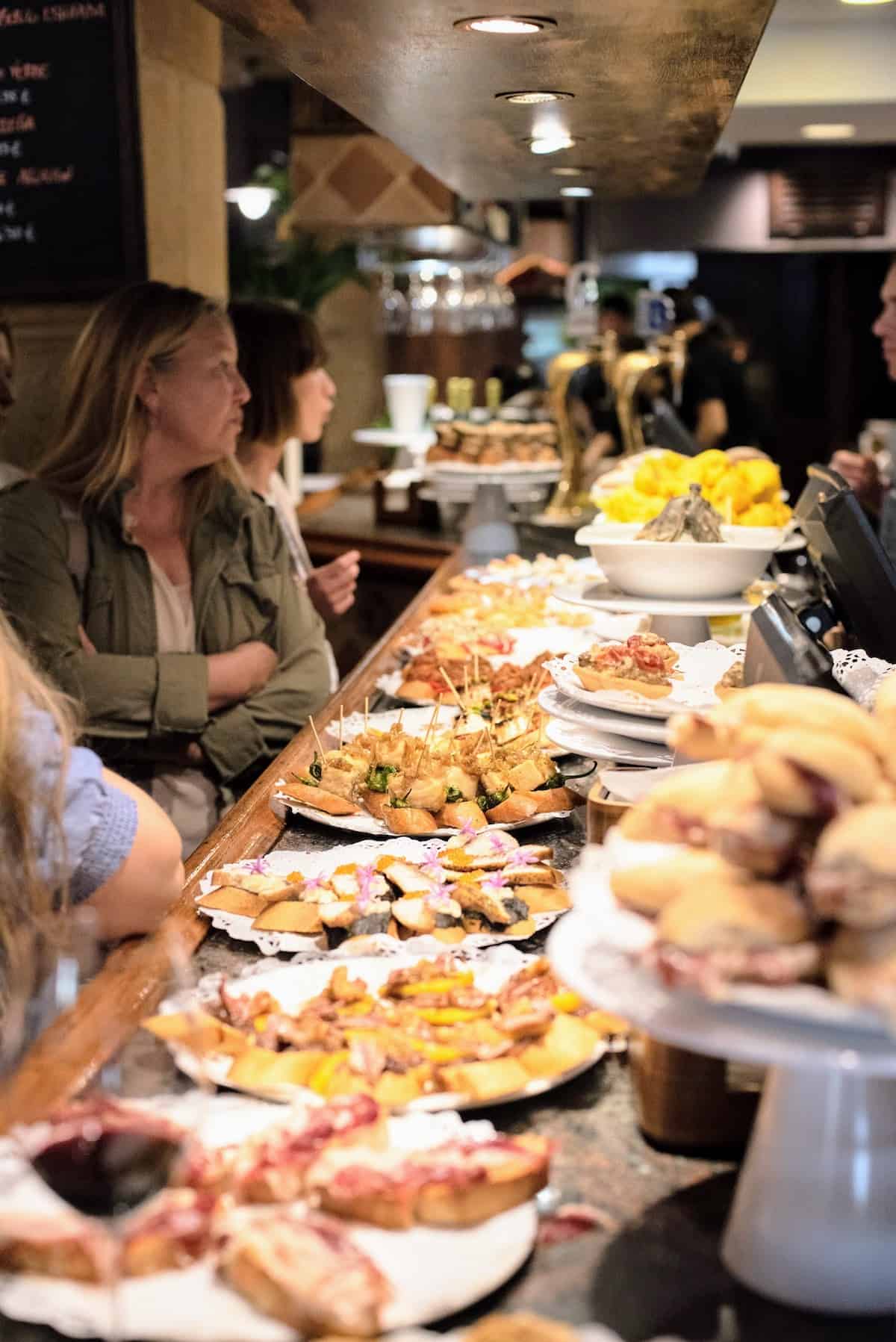 Bar top with several plates of small tapas style bites called pintxos.