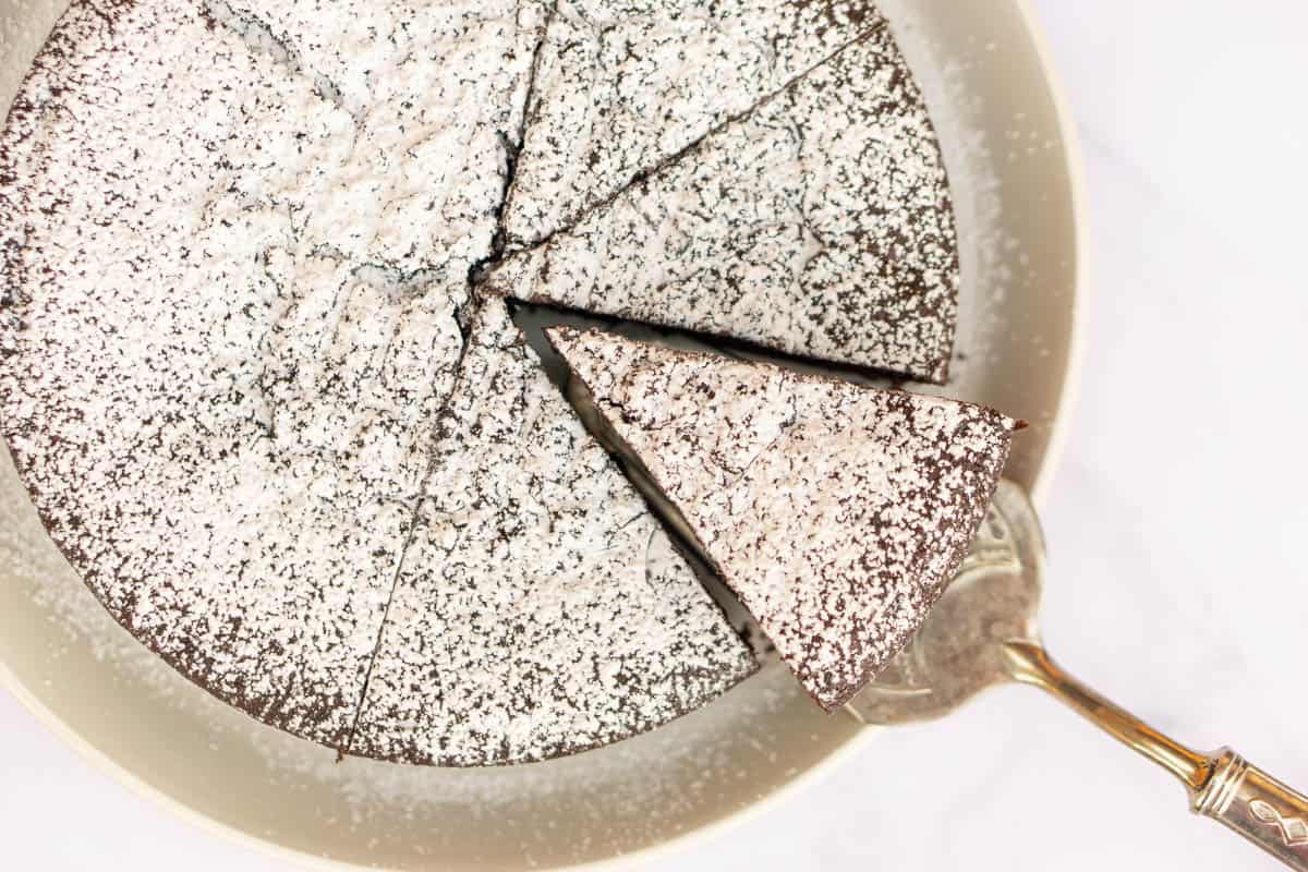 Large white dish with sliced chocolate cake and a silver cake server