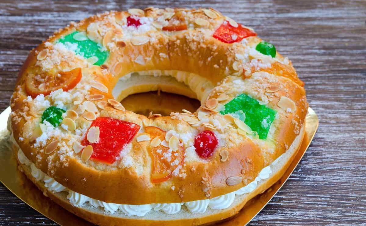 Round donut-shaped cake filled with whipped cream and decorated with red and green candied fruit