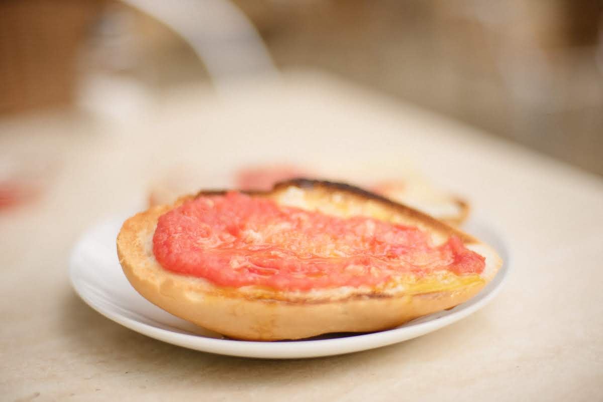 A slice of toasted bread topped with olive oil and pureed tomato.