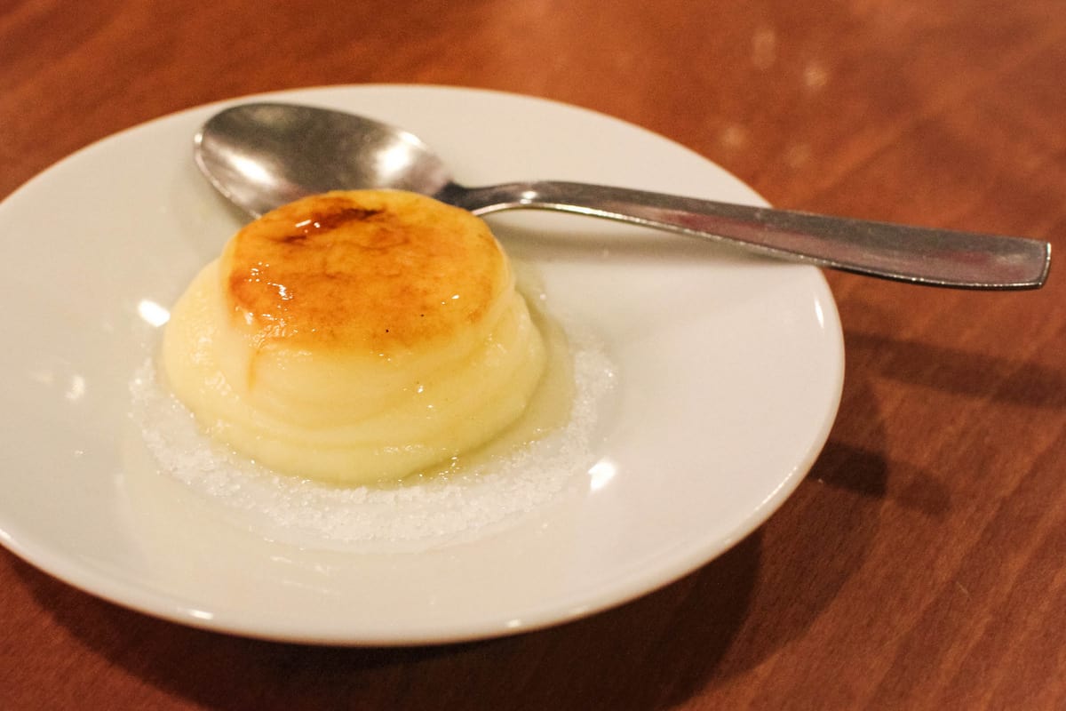 Flan on a white plate with a metal spoon