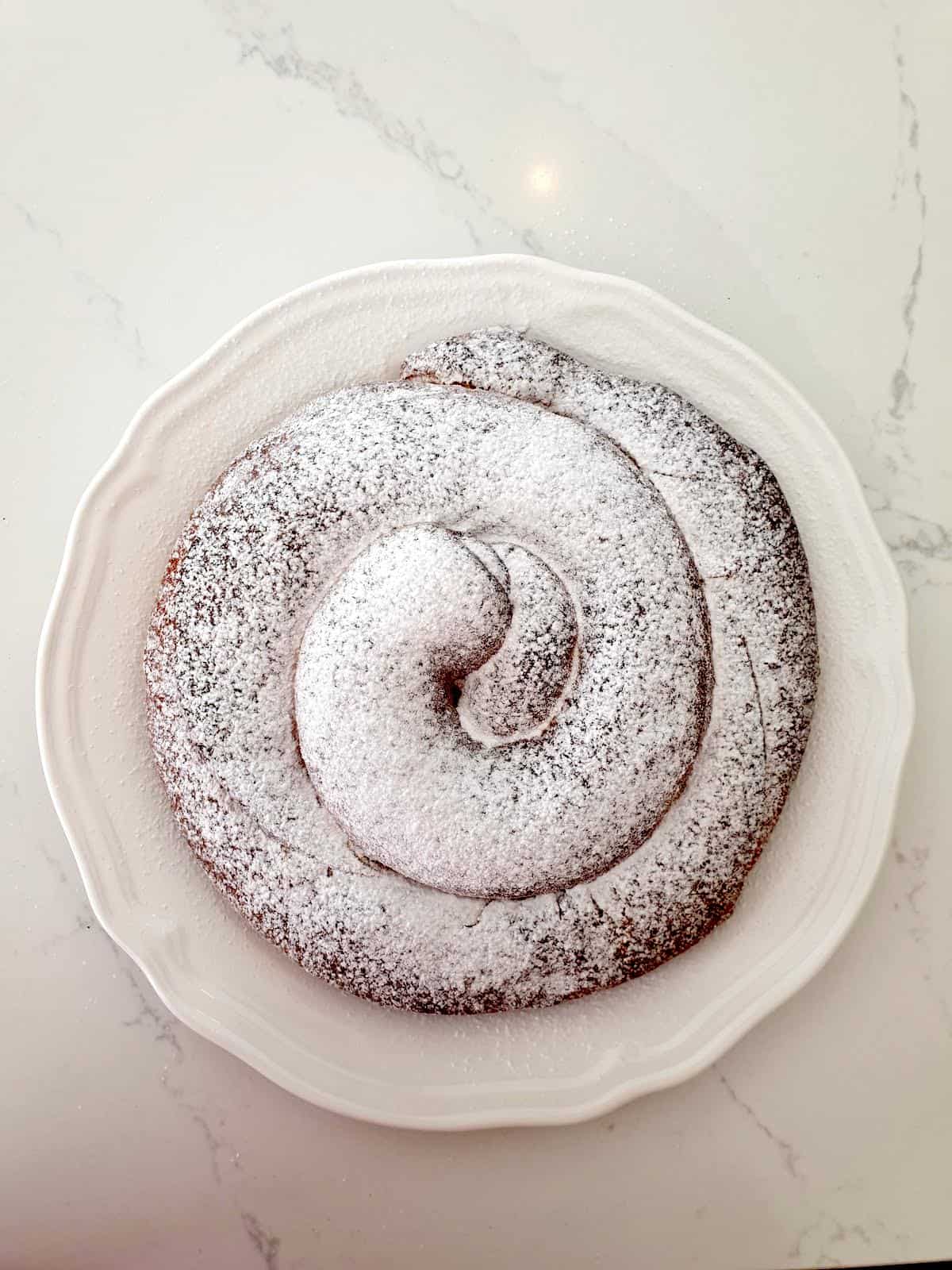 Overhead shot of a spiral-shaped pastry covered in powdered sugar.