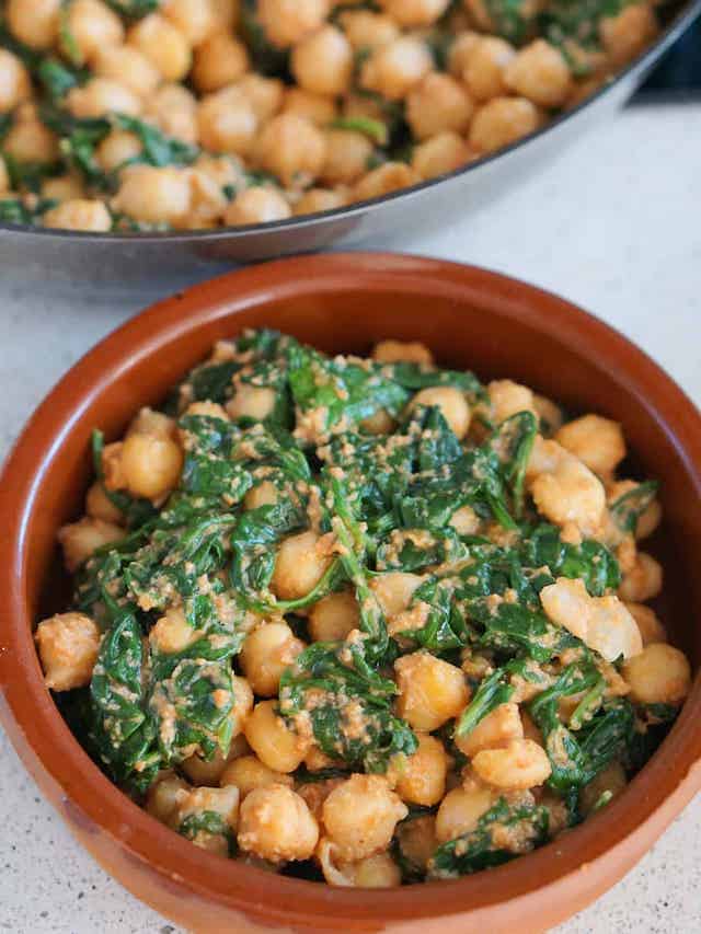 Individual serving of spinach and chickpea stew in a small terra cotta dish