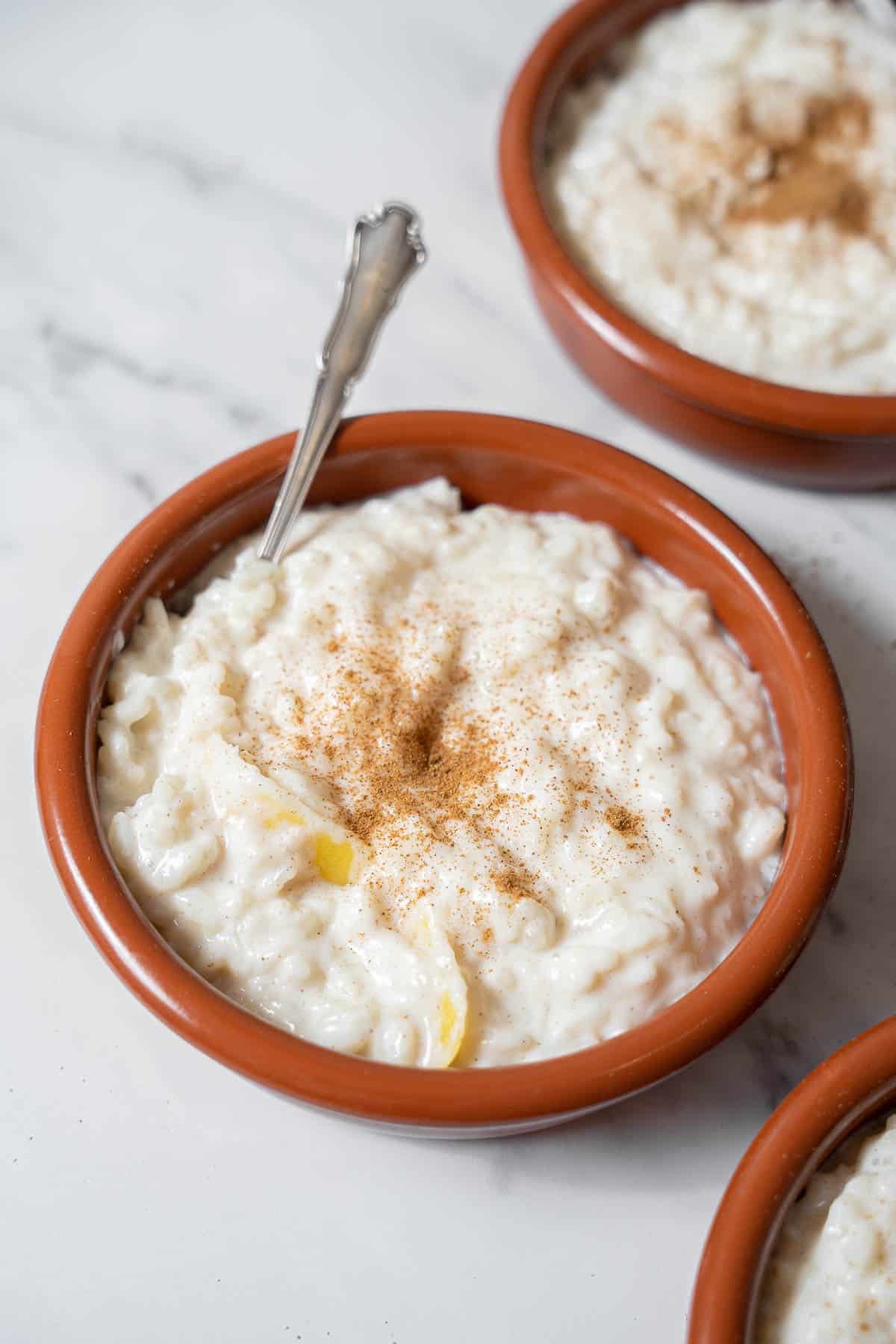 bowl of arroz con leche garnished with a piece of lemon peel.