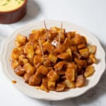 white plate of patatas bravas with toothpicks.