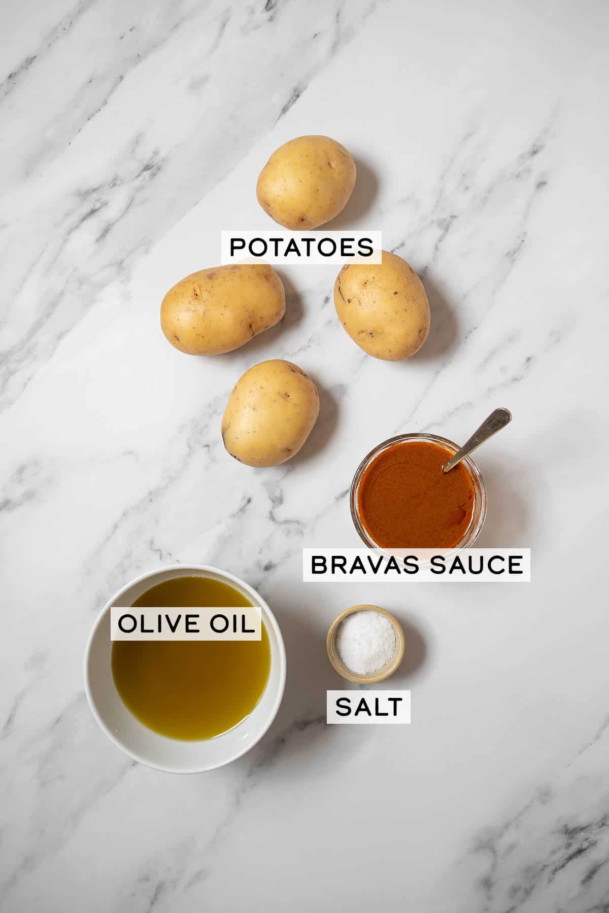 potatoes and bowls of ingredients for patatas bravas.