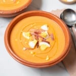 shallow bowl of salmorejo garnished with ham and boiled egg.