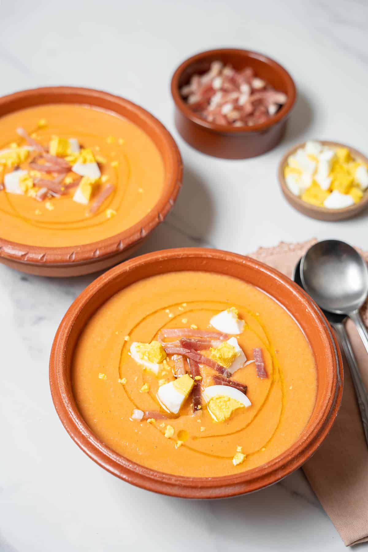 two bowls of salmorejo with two spoons.