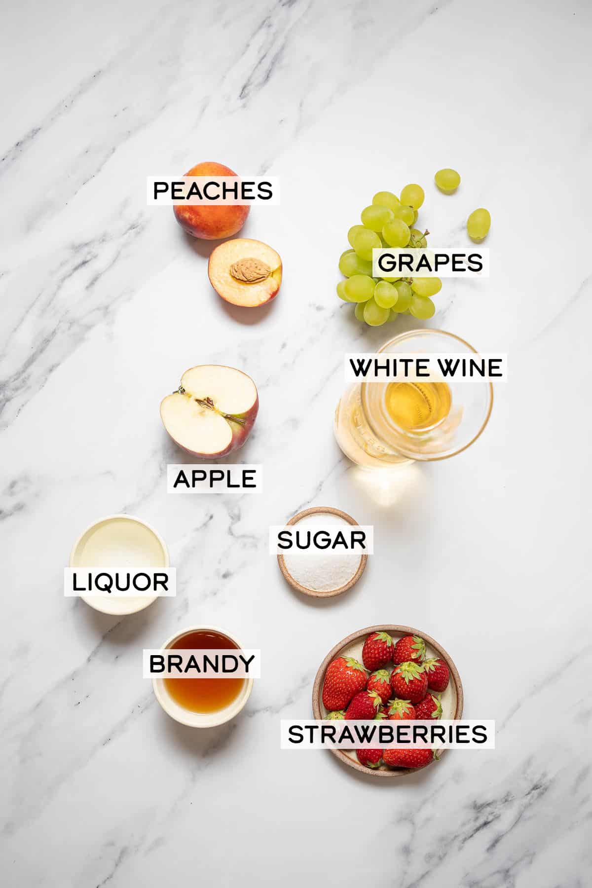 ingredients for white sangria on a white marble surface.