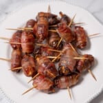 white plate of bacon wrapped dates with toothpicks.