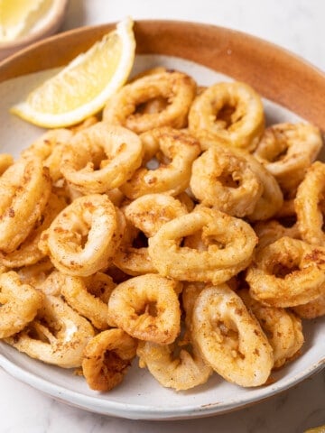 shallow bowl of calamares fritos with a lemon wedge.