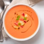 large bowl of gazpacho garnished with apple and tomato.