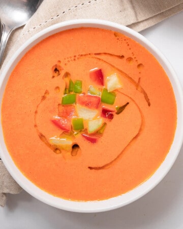 large bowl of gazpacho garnished with apple and tomato.